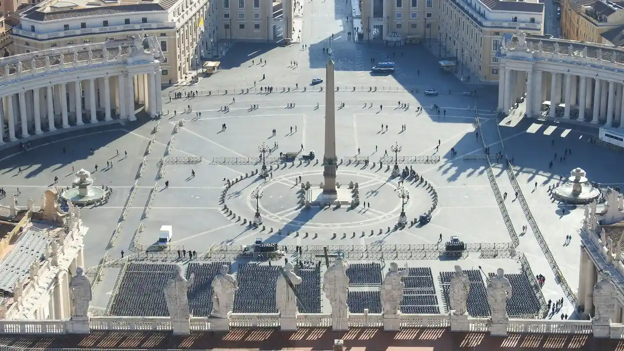 Aerial view of St. Peter’s Square at Vatican City, featuring the central obelisk, Bernini’s colonnades, and the forecourt of St. Peter’s Basilica with visitors walking across the historic plaza.