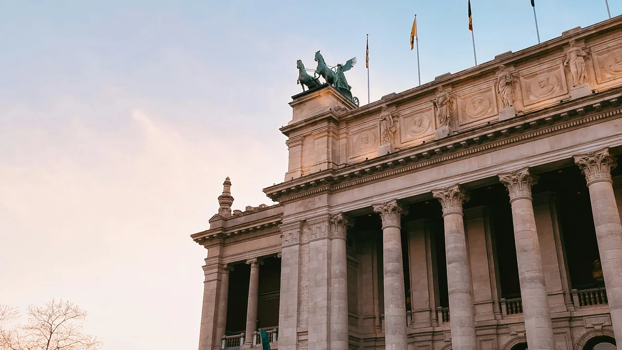 Parc du Cinquantenaire triumphal arch in Brussels featuring neoclassical columns and bronze quadriga statue at sunset