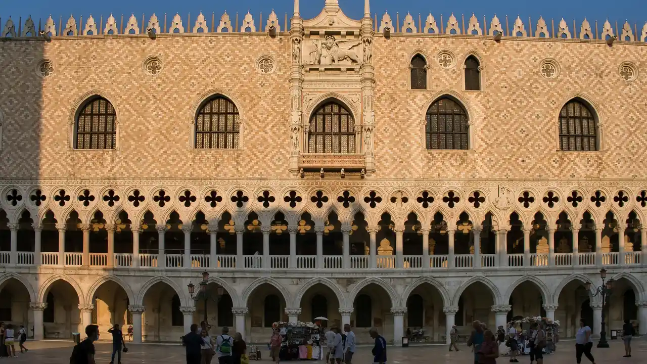 Doge’s Palace (Palazzo Ducale) in Venice, Italy, showcasing Venetian Gothic architecture with ornate arches, patterned stone façade, and visitors in the historic courtyard.