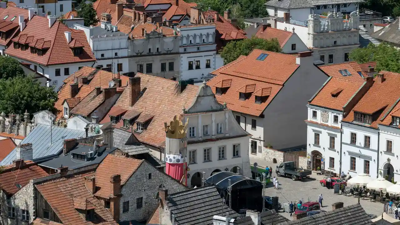 Aerial view of historic Kazimierz Jewish Quarter in Kraków, Poland, featuring red-tiled rooftops, preserved stone buildings, and a traditional town square showcasing medieval European architecture.
