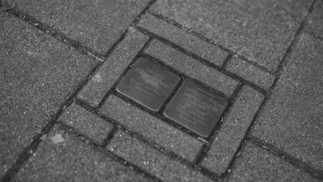 Close-up of two Stolpersteine memorial stones embedded in a sidewalk, commemorating Holocaust victims with engraved names and dates, symbolizing remembrance and historical memory in the Netherlands.