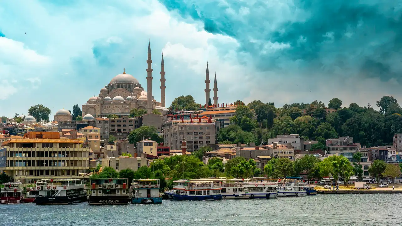 Istanbul city skyline with Suleymaniye Mosque and Bosphorus waterfront boats under dramatic cloudy sky Turkey travel destination