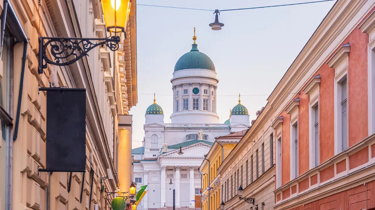 Helsinki Cathedral with its iconic green dome and neoclassical façade viewed along a narrow historic street in Helsinki, Finland at sunset