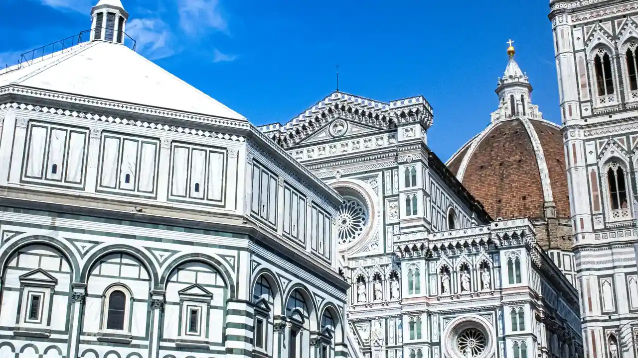 Florence Cathedral Duomo complex with ornate marble facade and Brunelleschi dome under blue sky in Florence Italy