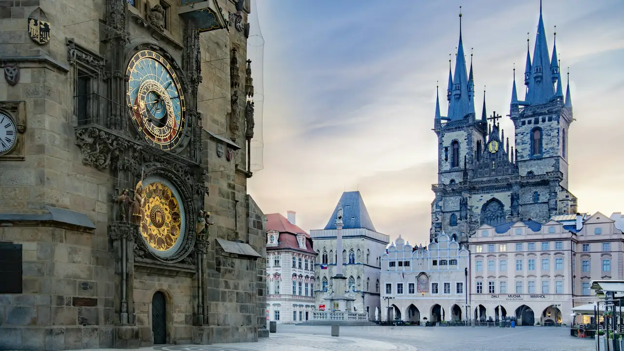 A close-up view of the Prague Astronomical Clock (Orloj) mounted on the side of the Old Town Hall tower. The intricate medieval clock features a large astronomical dial and a lower calendar dial.
