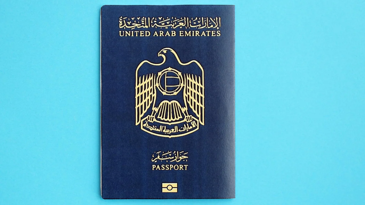 United Arab Emirates passport cover with gold national emblem and Arabic text on a dark blue background, official UAE travel document.