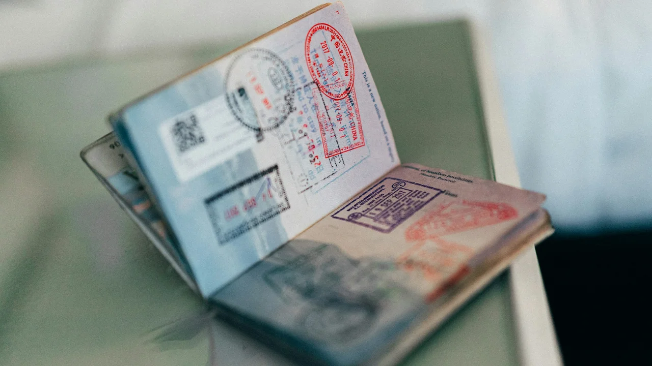 Open passport showing multiple visa and immigration stamps, representing previous international travel history, Schengen visas, and proof of prior overseas journeys.