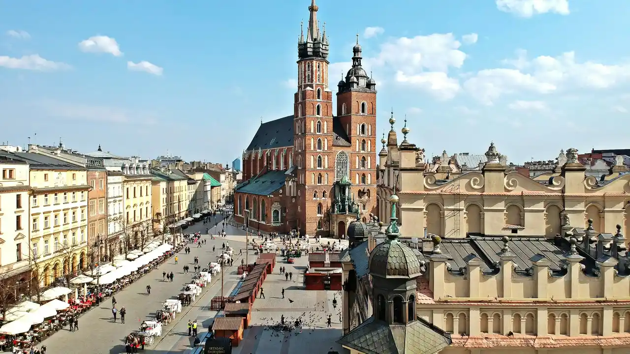 Aerial view of Kraków Main Market Square with St. Mary’s Basilica, historic townhouses, and bustling city life in Kraków, Poland.