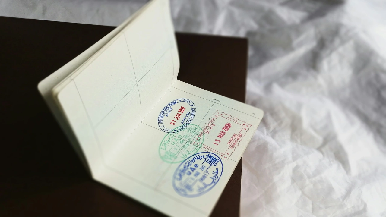 Open passport with multiple international immigration entry and exit stamps on blank visa pages placed on wooden surface