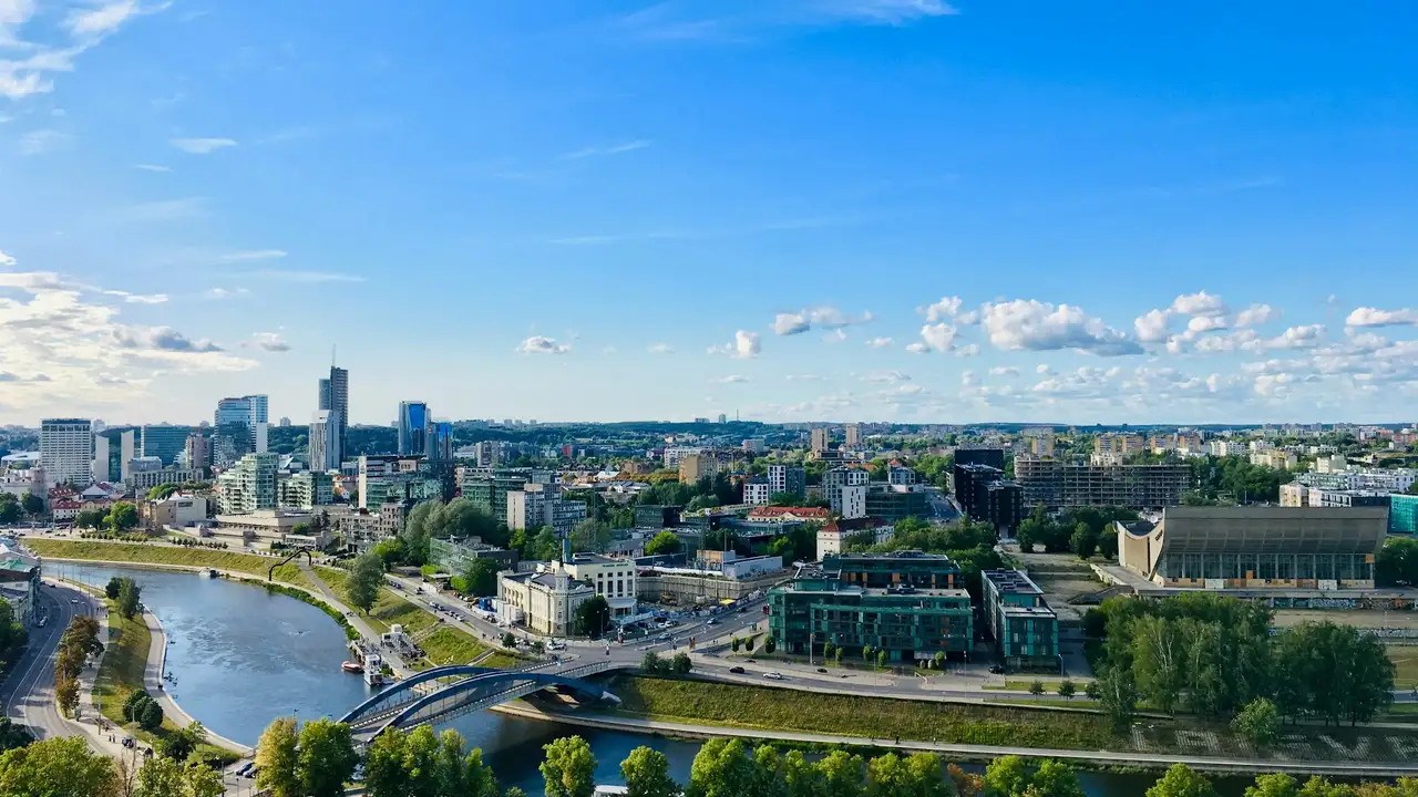 Vilnius city skyline with Neris River and modern business district, panoramic view of Lithuania capital featuring bridges, high rise buildings, and green urban landscape