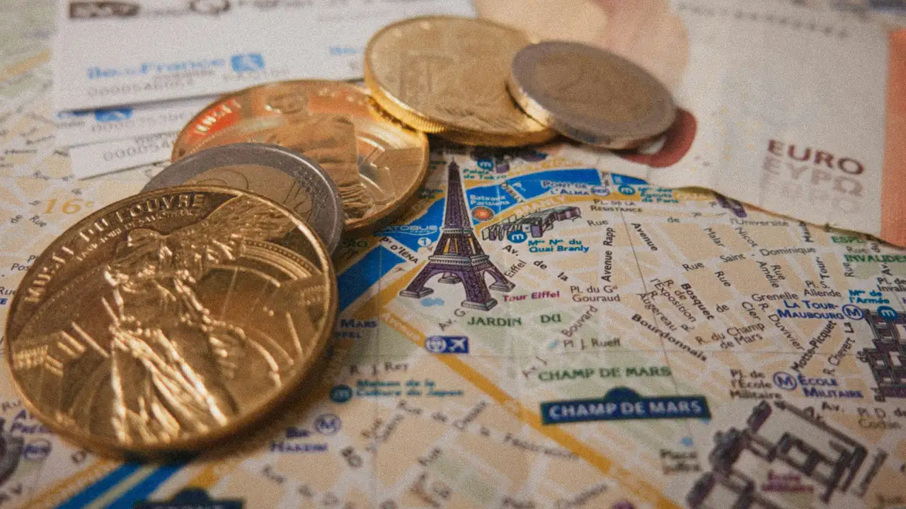 Euro coins placed on a Paris city map near the Eiffel Tower, representing travel cash, prepaid cards, and budgeting money for trips in Europe.