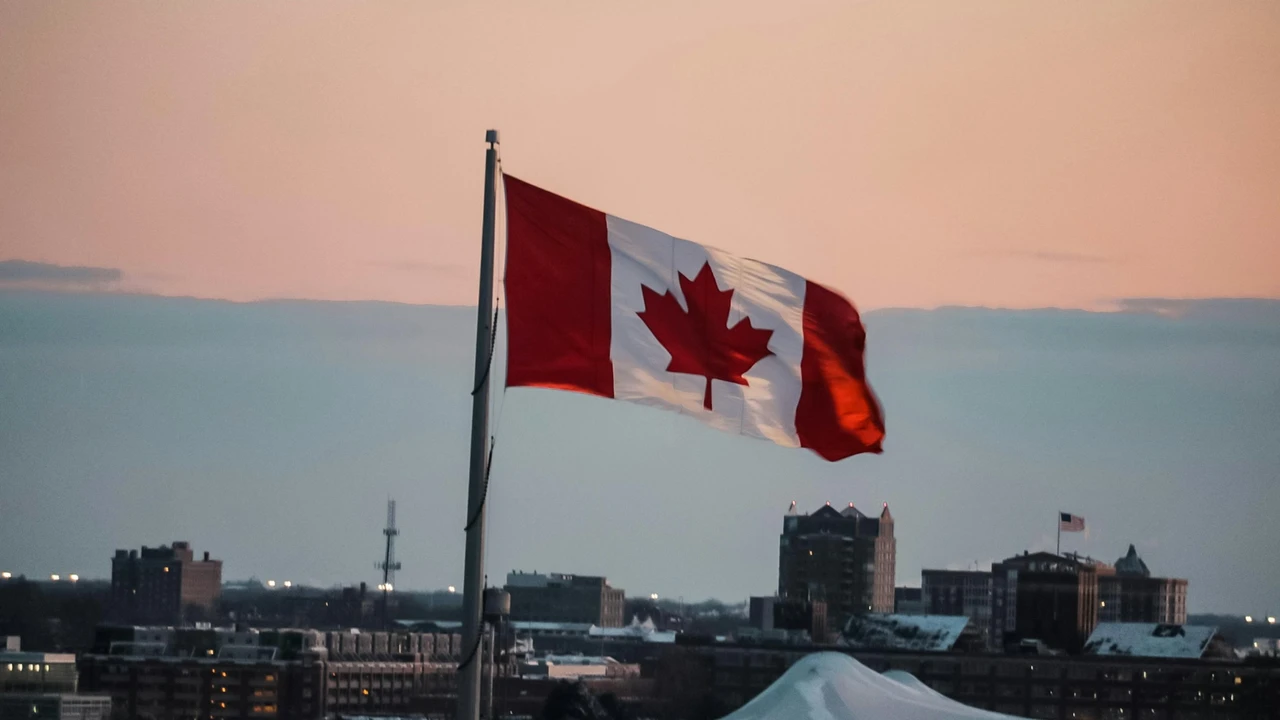 Canadian national flag waving on a flagpole at sunset with an urban city skyline in the background, symbolizing Canada study visa requirements and opportunities for international students from India.