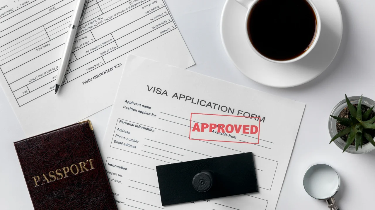Approved visa application form with passport, coffee cup, pen, and office desk setup representing successful travel or immigration process