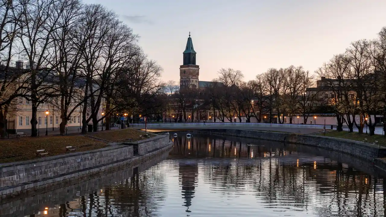 Turku Cathedral and Aura River at sunset in Turku Finland with historic buildings and illuminated riverside reflections