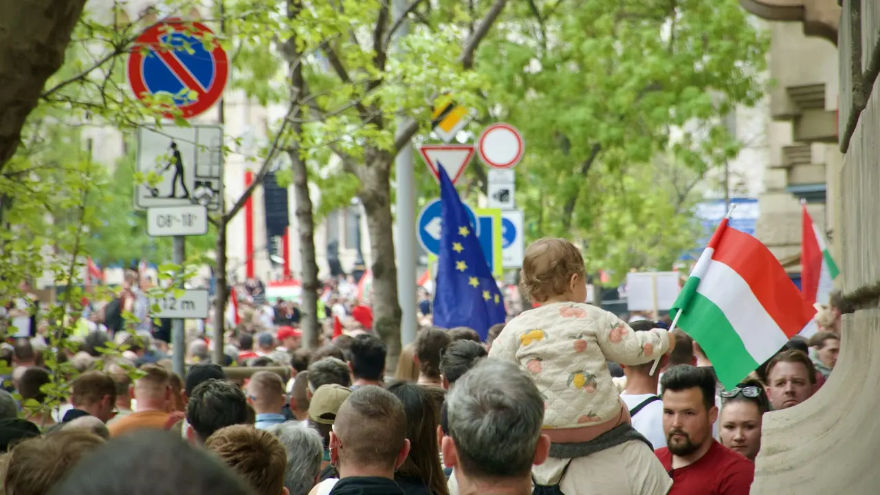 Crowd of people at a public demonstration in Hungary, with a child holding the Hungarian national flag and European Union flags visible, representing civic protest and political gathering in Budapest.