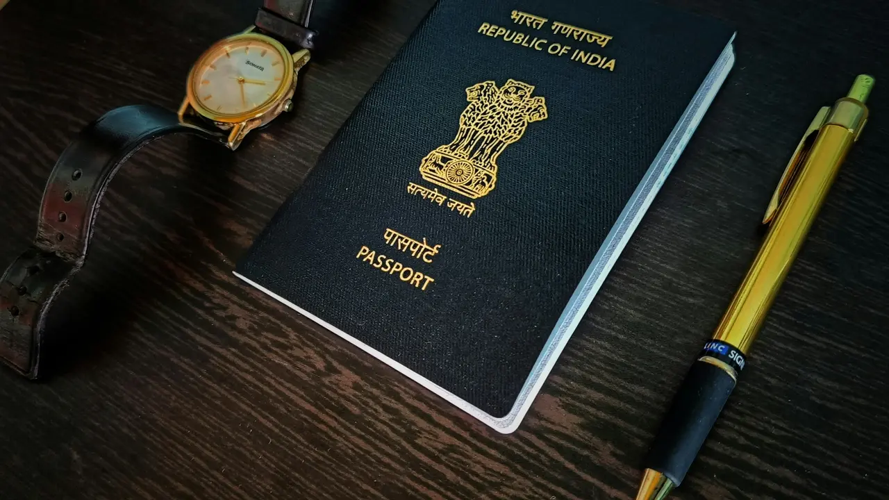 Indian passport placed on a wooden table alongside a wristwatch and pen, symbolizing valid travel documents and visa application preparation.