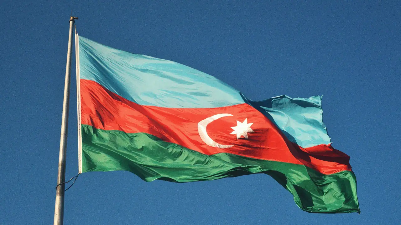 Azerbaijan national flag waving against clear blue sky representing Azerbaijan travel and visa information