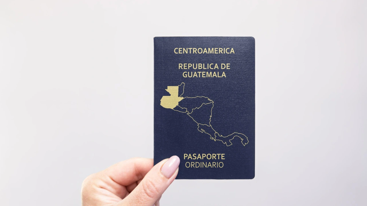 Guatemalan passport (República de Guatemala) – Central America ordinary passport with gold map design on navy blue cover held in hand.