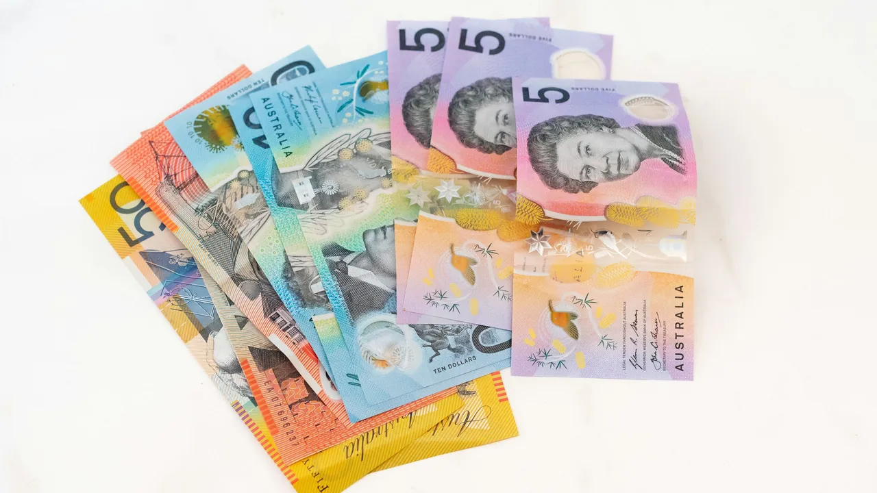 “Australian dollar banknotes (AUD) including $5, $10, $20 and $50 notes fanned out on a white background, representing Australia currency, travel costs, visa fees, and tourism expenses.