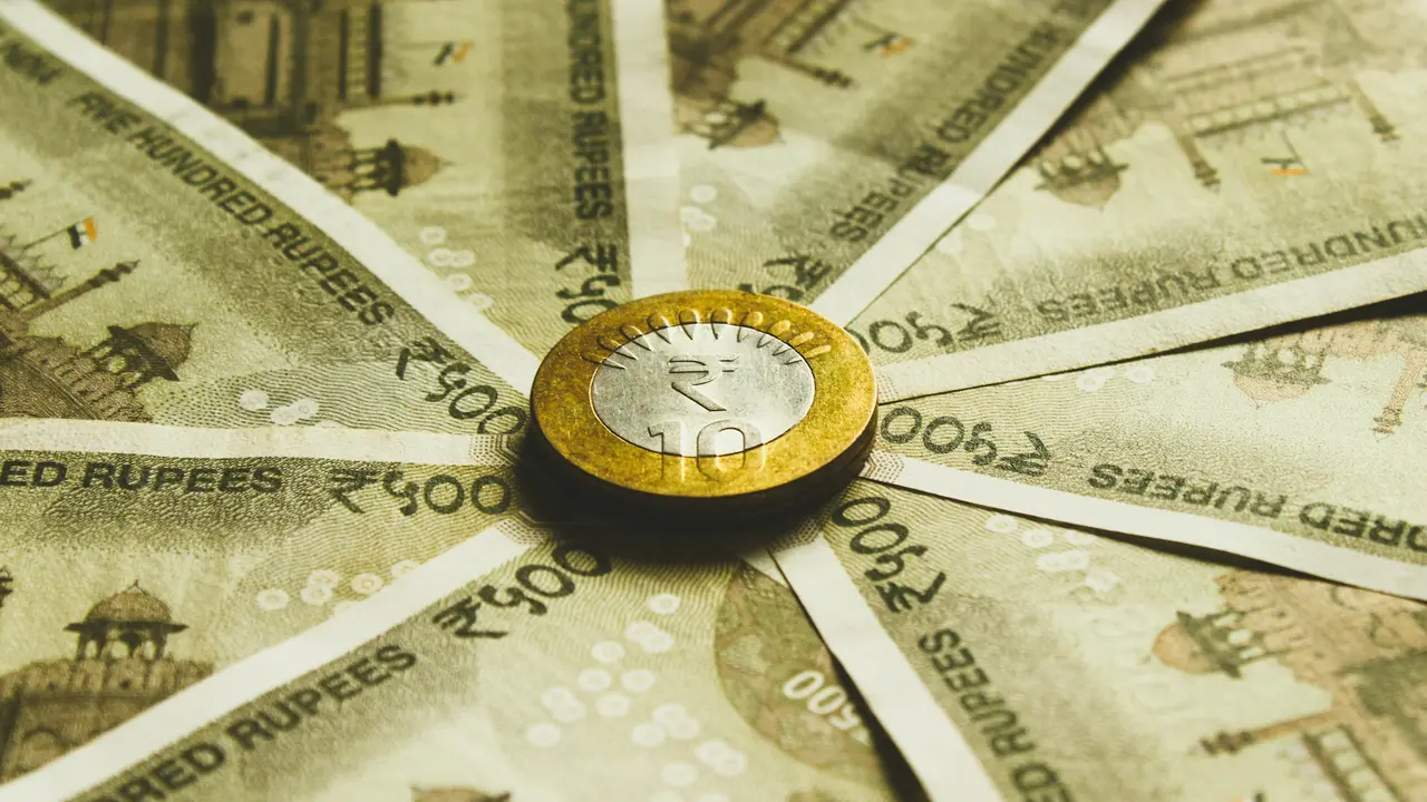 Close up of Indian 10 rupee coin placed on 500 rupee banknotes spread in circular pattern representing Indian currency, finance, economy and investment concept
