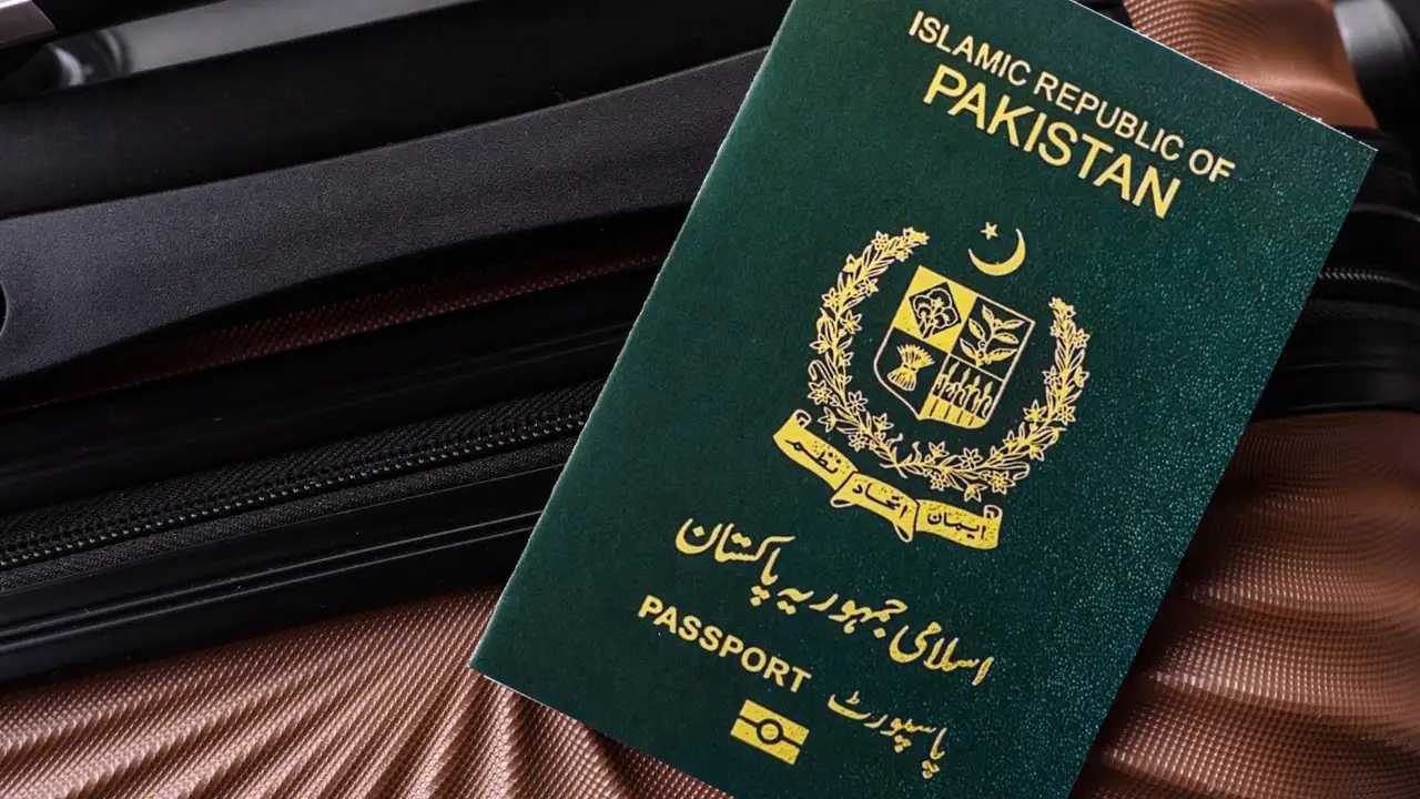 Pakistan passport (Islamic Republic of Pakistan) with gold national emblem on green cover, placed on open suitcase for international travel.