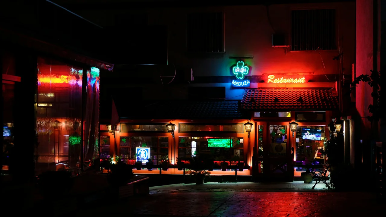 Neon lit Irish Meduza restaurant exterior at night with colorful red and green signage and illuminated street scene