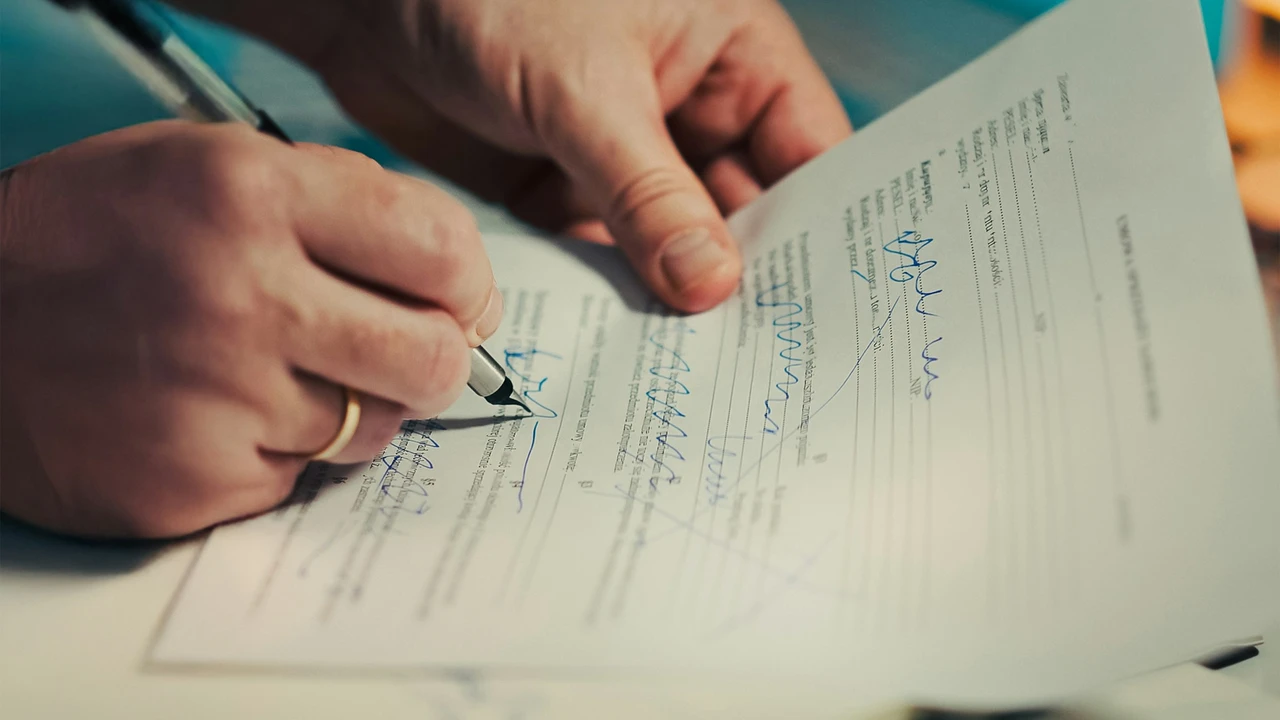 Close-up of a person signing official visa application documents with handwritten notes and corrections, representing common visa rejection reasons due to incomplete or incorrect paperwork.