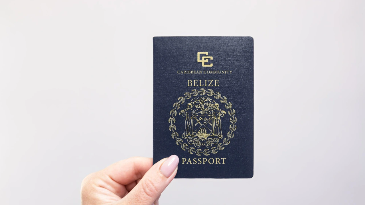 Hand holding a Belize passport with Caribbean Community emblem on a neutral background, representing Belize citizenship, international travel, and official government identification document.