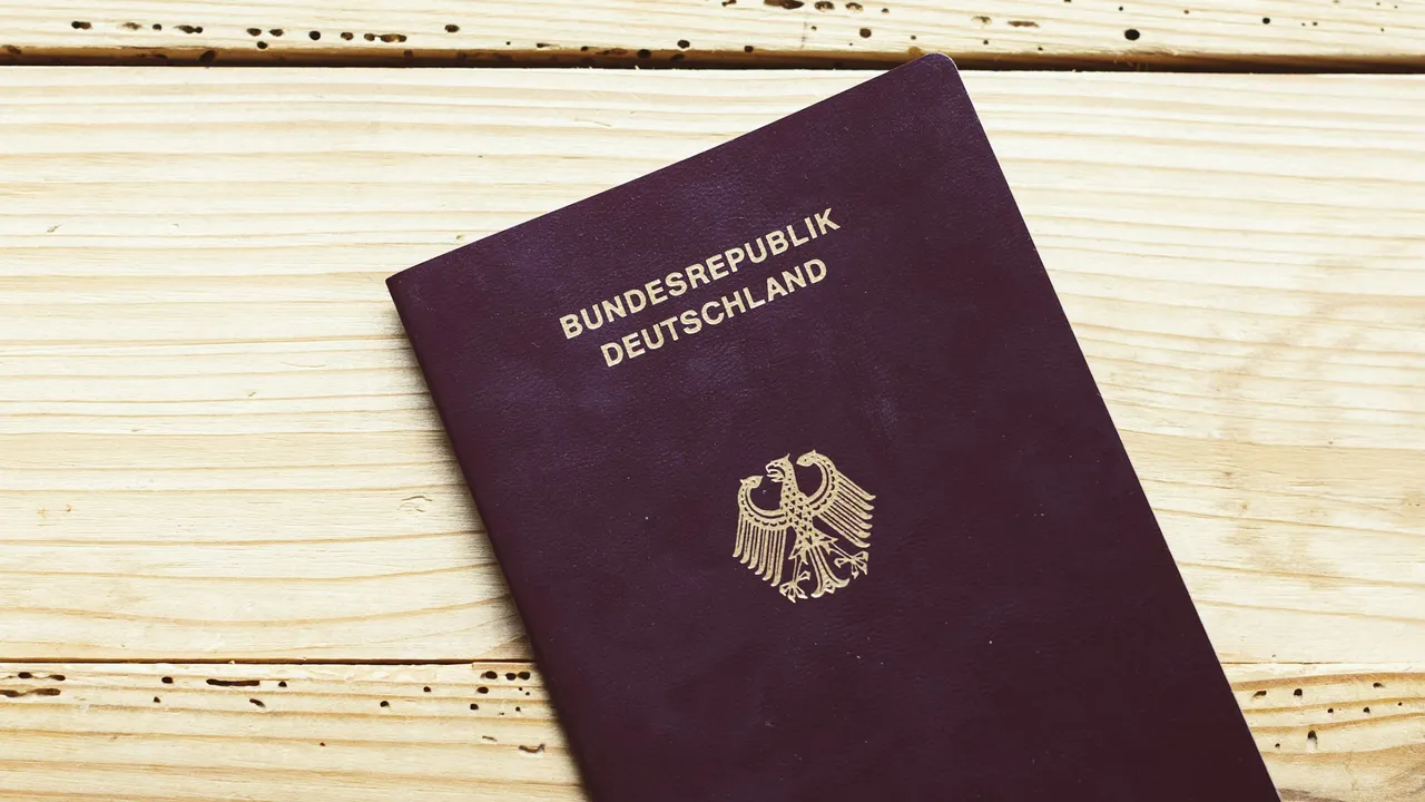 German passport (Bundesrepublik Deutschland) with the federal eagle emblem placed on a light wooden surface, symbolizing travel or visa documentation.