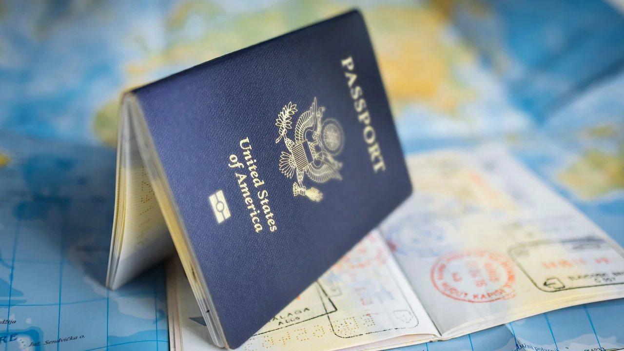 United States passport standing open on a world map, with visible visa stamps on the pages, symbolizing international travel and visas.