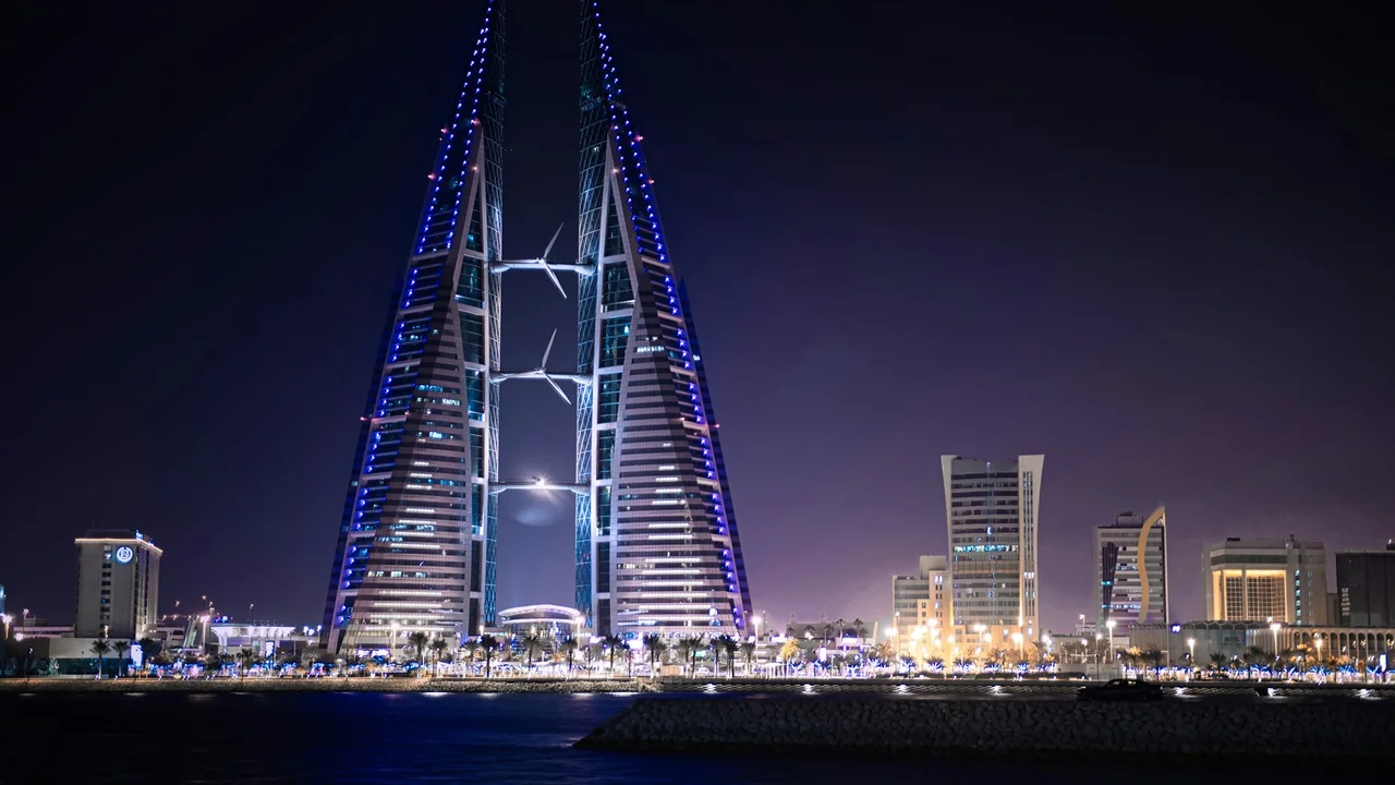 Bahrain World Trade Center illuminated at night with twin towers and integrated wind turbines, showcasing Manama skyline, modern architecture, and Bahrain business district.