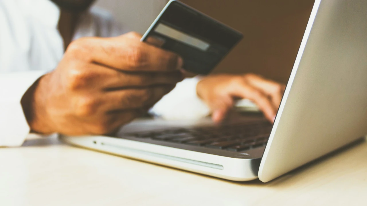 Person making an online payment with a credit card while using a laptop, representing payment of visa application fees.