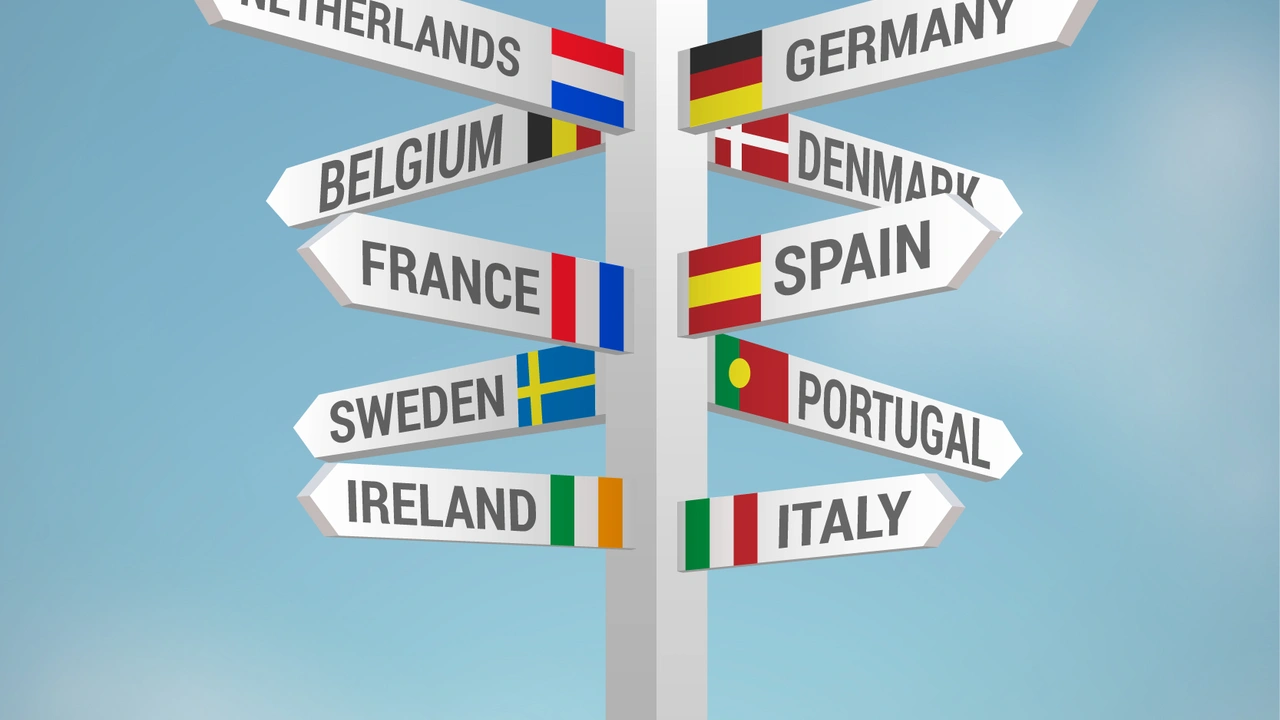 Directional signpost with European country names and flags including Germany, France, Spain, Italy, Netherlands, Belgium, Denmark, Sweden, Ireland, and Portugal against a blue sky background, symbolizing Europe travel and tourism.