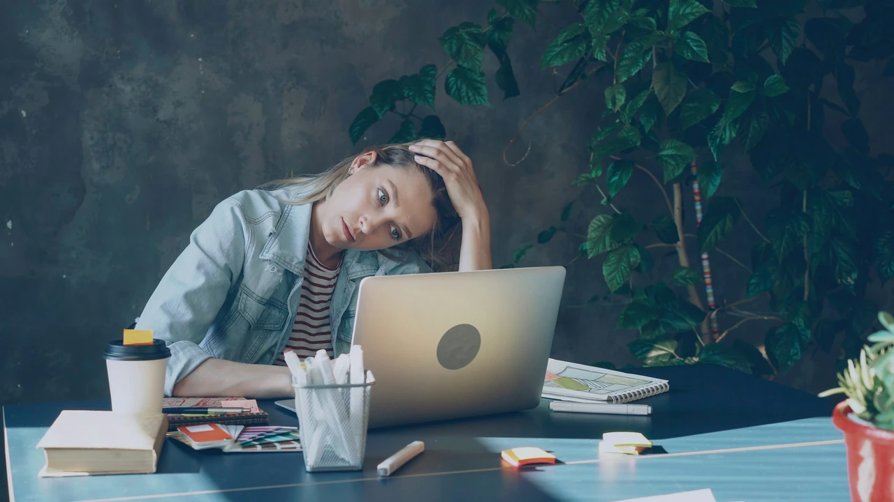Frustrated woman reviewing documents on a laptop at her desk, representing common reasons for Czech Republic visa rejection or application denial.