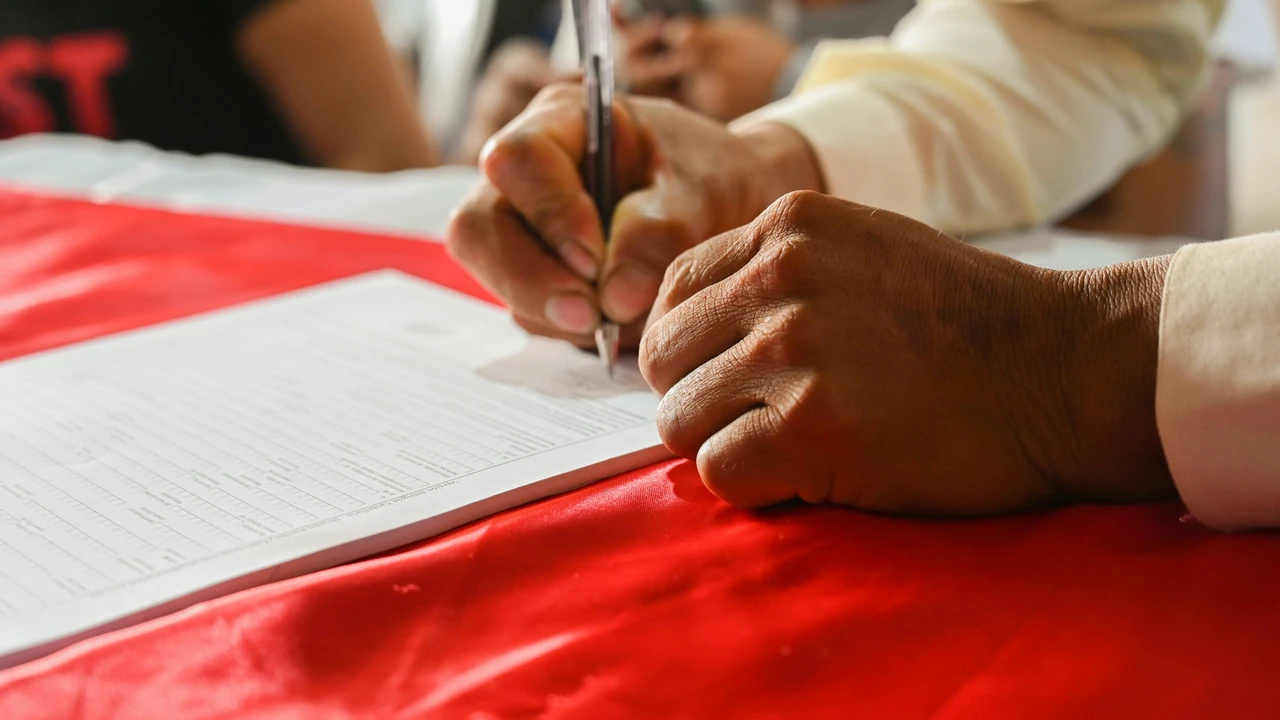 Close-up of a person signing official documents on a desk, representing the work visa and work permit application process, legal paperwork, and employment authorization.